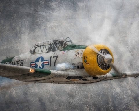 Vintage aircraft flying through a cloudy sky with a prominent yellow engine.