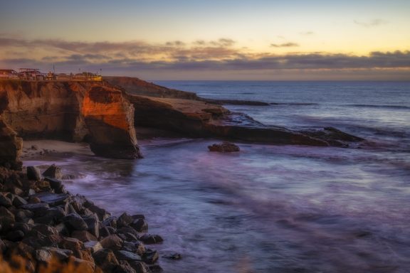 Rocky coastal landscape with gentle waves and a serene sunset sky.